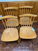 Four spindle-back chairs grouped together showing overall design and wear
