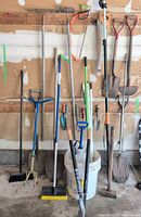 Overall view of long-handled tools, broom, rakes, shovels, sprayer