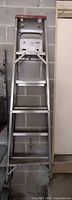 Ladder folded against wall showing full height and red safety feet