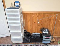 Tall plastic drawer tower, desk lamp, printer on small drawer unit, mesh organizers, cables