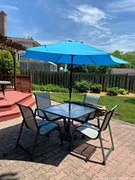 table, four chairs and blue umbrella on patio
