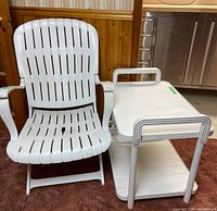 front view of white folding patio chair beside matching two-tier table
