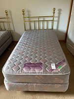 Twin mattress on box spring with brass headboard visible