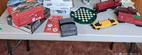 Tabletop view of puzzles, train cars, game mat, hats, dartboard and accessories