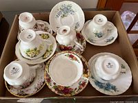 Box containing seven teacup and saucer sets showing tops and undersides