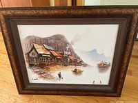 Framed painting resting on floor showing full frame and artwork