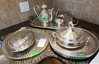 Group view of all silver-plated pieces and glass plate on countertop