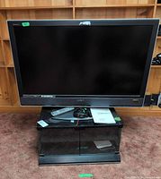Front view of Sony Bravia TV on glass stand with remote, cables and manual visible