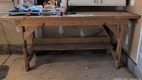 Front view of full wooden workbench showing top surface, legs, lower shelf