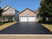 Freshly sealed two-car driveway in front of brick house