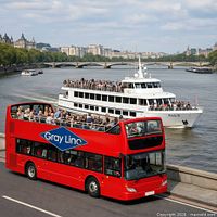 Gray Line red double-decker bus with sightseeing boat in background