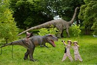 Promotional image with animatronic dinosaurs and visitors