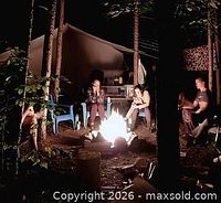 Nighttime campfire scene outside safari tent with guests seated