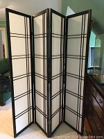 Full view of the four-panel rice paper folding room divider standing upright showing black wooden frame and white paper insert with grid lines.