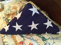 Tri-folded US flag showing white stars embroidered on blue field, placed on a floral bedspread.
