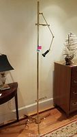 Full view of brass finish easel floor lamp standing on hardwood floor