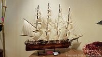 Front view of four-masted ship model on stand with sails rigged