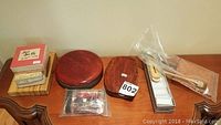 Overall view of all items arranged on table: paper pack, tin container, trays, and bagged ink sticks