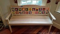 Front view of natural wood bench with tiled backrest featuring children's paintings.