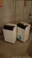 Two units side by side on concrete basement floor against cinder block wall.