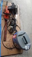 Photo of the complete set laid on cardboard showing all five tools: hedge clippers, electric saw, planer, handheld router, and a hard case for the larger router kit.