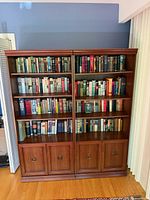 Front view of both wood bookcase cabinets filled with books (books not included)
