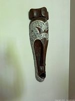 Front view of elongated carved wooden wall mask on wall