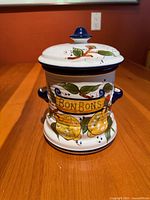 Front view showing Bon Bons lettering, fruit design, lid and handles