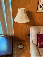 Full view of chrome floor lamp with shade beside sofa
