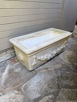 Front angled view of cast stone planter showing garland detail and rim