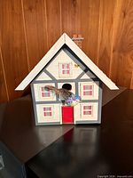 front view showing half-timber facade, red door, windows, entrance, decorative bird and butterfly