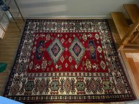 Full rug showing red field and cream border with geometric patterns