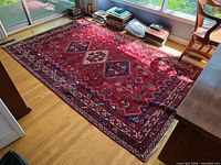 Full view of red Persian rug on hardwood floor