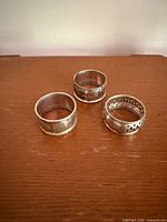 Three sterling silver napkin rings, assorted designs, top view