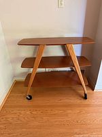 Front view of three-tier wood shelf on casters