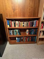 Front view of wood bookcase filled with books (books not included)