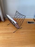 Full view of metal magazine rack standing on floor