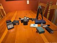 Overall lot on table showing camera, flashes, tripod, bracket, boxed accessories