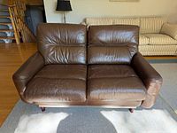 Front view of brown leather loveseat showing cushions and overall style