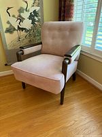 Front view of pink upholstered armchair with wood arms and legs