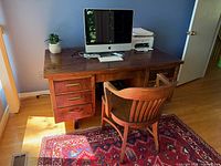 Front view of wood desk with chair showing drawer configuration and surface