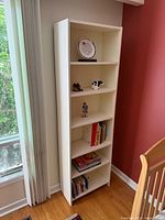 Full view of white bookcase with five shelves, contents shown for scale