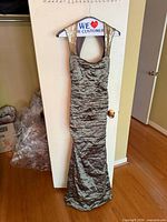 Front view of full dress hanging on hanger showing ruched body and gold sequin straps