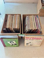 Two boxes filled with vinyl LPs plus two showcased albums at front