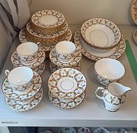 Full set displayed showing stacks of plates, bowls, teacups with saucers, creamer and sugar bowl