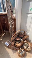 Group view of driftwood pieces, wicker baskets, shells and stones