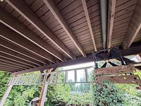Aluminum extension ladder hung under deck with folding sawhorse beside
