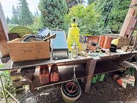 Wide view of shelving with tools, sprayer, seat-kneeler, fuel cans, pots