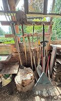 Group of hanging garden tools including shovels, rakes, fork, hoe