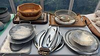 Overall view of stacked metal trays, bamboo baskets, wire mesh bowl, wood tray